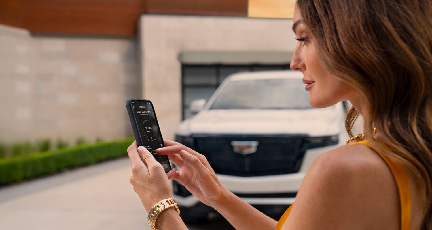 lady checking her mobile with a Cadillac vehicle background | Motor Werks Cadillac in Barrington IL